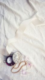 Directly above view of pocket watch on white bed