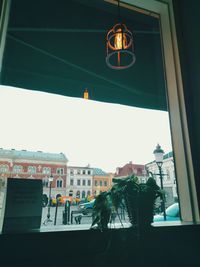 Low angle view of illuminated pendant light against building in city