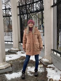 Full length portrait of smiling woman standing in snow