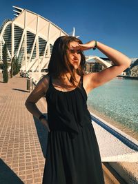 Woman standing by swimming pool against sky