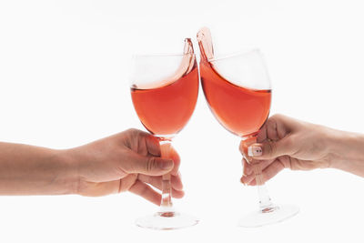 Cropped hand holding wineglass against white background