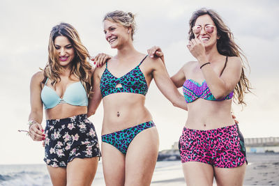 Happy friends wearing bikini while enjoying together at beach
