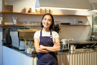 Portrait of young woman standing in kitchen