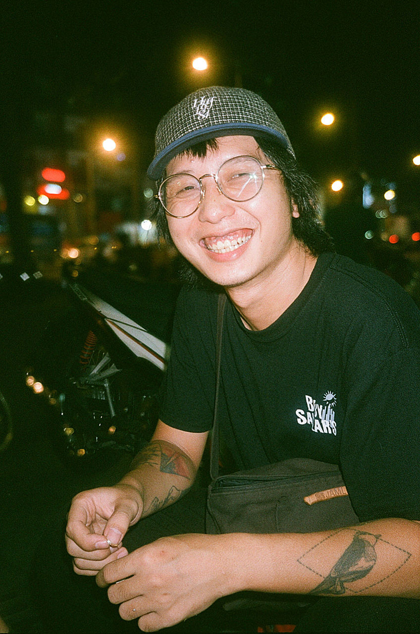 portrait, smiling, illuminated, one person, looking at camera, night, real people, front view, lifestyles, glasses, casual clothing, leisure activity, young adult, happiness, hat, transportation, focus on foreground, cap