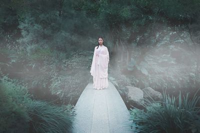 Portrait of young woman standing in forest