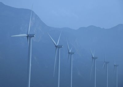 Wind turbines on mountain against blue sky