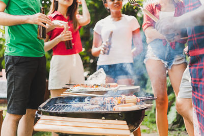 Friends enjoying barbecue while standing outdoors