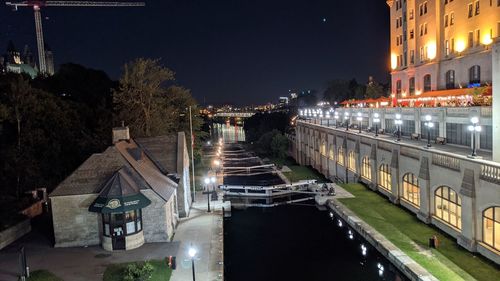 Illuminated buildings by canal in city at night