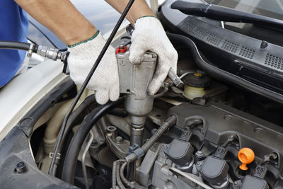 Cropped hand of mechanic repairing car in garage