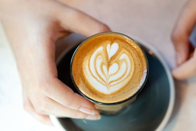 Aromatic cup of coffee in female hands, overhead closeup view