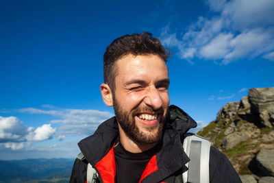 Portrait of smiling young man against blue sky