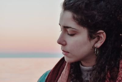 Close-up portrait of woman looking away against sky