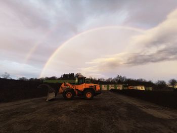 Scenic view of rainbow over road against sky during sunset