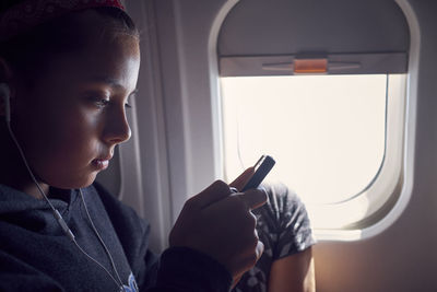 Girl using mobile phone while traveling in airplane