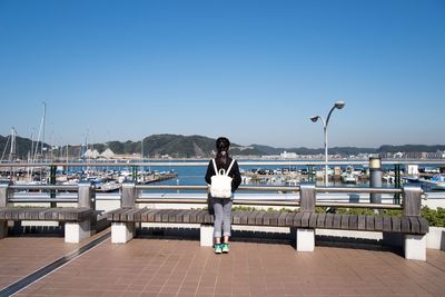 Full length portrait of young woman standing against sea