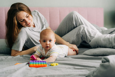 Caring tender mommy with a baby on the bed in the bedroom.