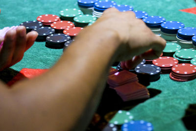 Cropped image of hand playing poker chips on table