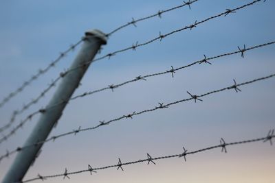 Low angle view of barbed wire against sky