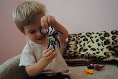 Cute boy playing with toy while sitting on sofa at home