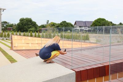 Side view of woman crouching on built structure