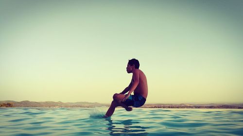 Full length of young woman in sea against clear sky