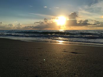 Scenic view of beach against sky at sunset