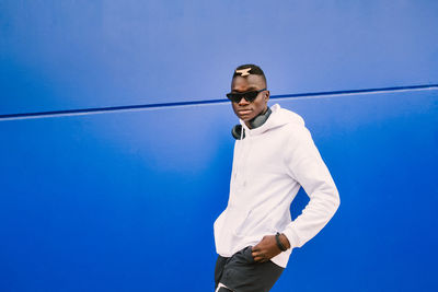 Portrait of man standing against blue background