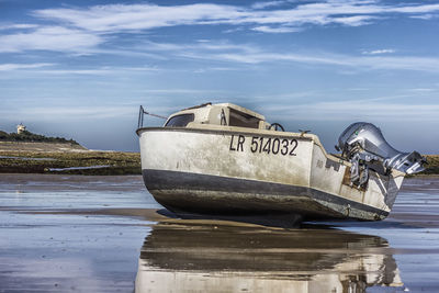 Boat moored at beach against sky