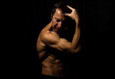 Man looking away while standing against black background