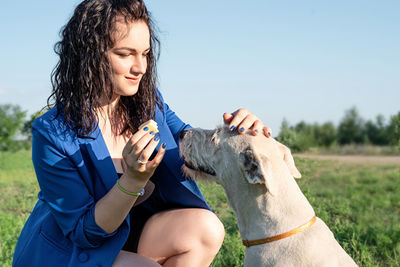 Pet care. pet adoption. young woman feeding her dog in the park in a summer sunny day