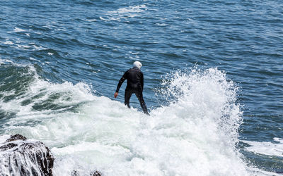 Rear view of man surfing in sea