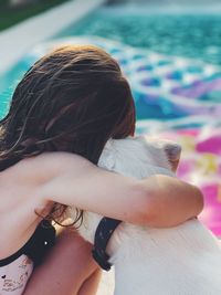 Rear view of girl sitting with dog outdoors