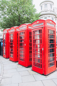 Red telephone booth on sidewalk in city