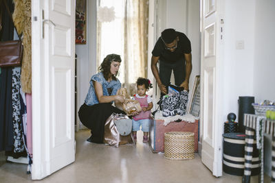 Daughter looking at mother and father packing luggage at home