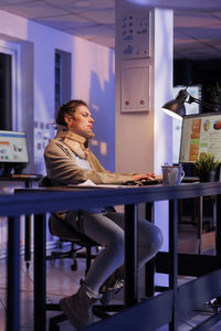 Woman using laptop while sitting on table