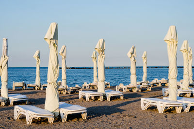 Deck chairs on beach against clear sky