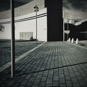 Empty footpath by street against buildings in city