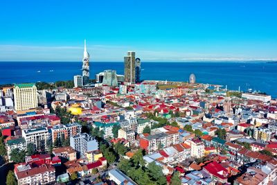 High angle view of townscape by sea against blue sky