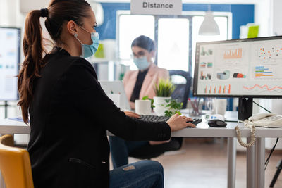 Side view of female friends using laptop while sitting in cafe