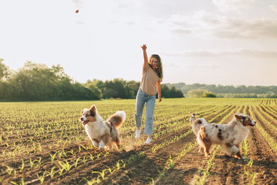 Happy young woman playing with her dogs outdoors in the countryside