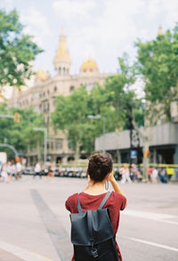 Rear view of man standing on road in city