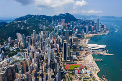 Aerial view of city by sea against sky