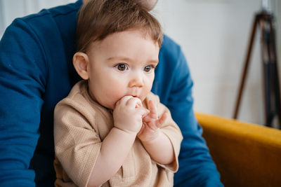 Close-up of cute baby boy lying on sofa at home