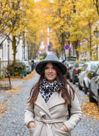 Portrait of young woman standing against trees