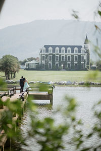 Rear view of couple standing on pier over lake against sky