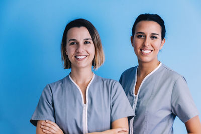 Portrait of female dentists smiling against blue background