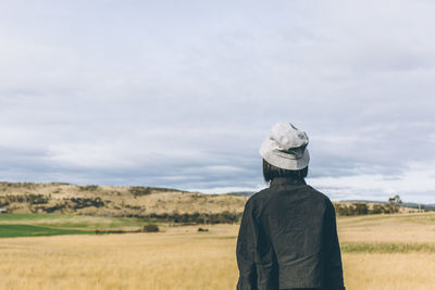 Rear view of woman standing on field against sky