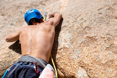 Rear view of shirtless man climbing rock