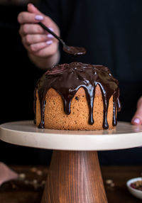 Close-up of hand holding chocolate cake on table