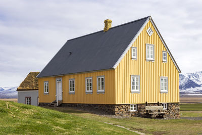 Yellow building of the glaubaer farm and museum against snowy mountains and sky